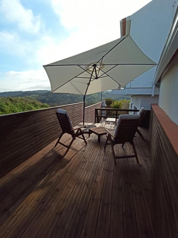 a patio with two chairs and a table and an umbrella at Refúgio da Sancheira Grande in Óbidos