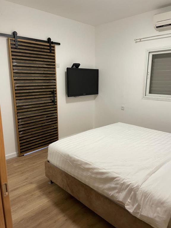 a bedroom with a bed and a flat screen tv at BALCONY HATMARIM in Eilat