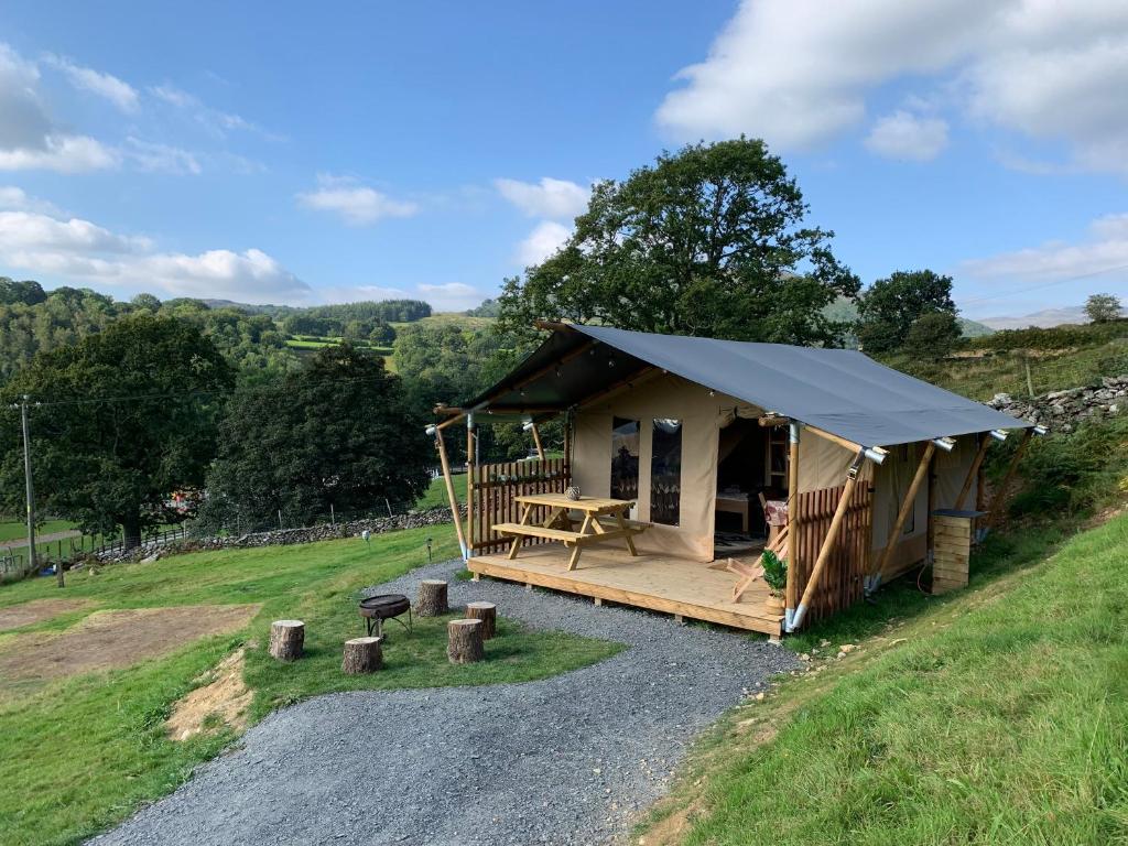 a cabin with a blue canopy on a gravel road at Safari Tent with Hot Tub in heart of Snowdonia in Dolgellau
