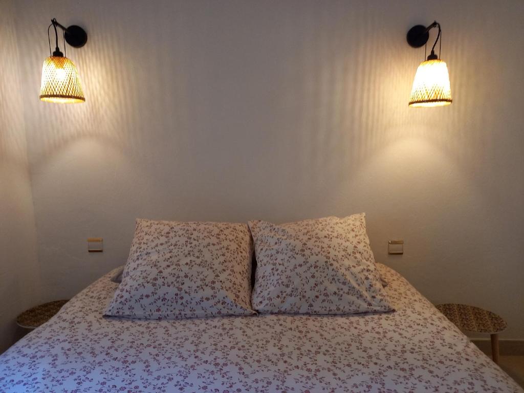 a bedroom with a bed with two pillows and two lights at Résidence Royal Palmeraie in Aubagne