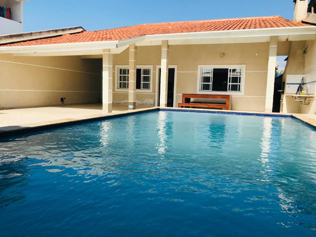 - une piscine en face d'une maison dans l'établissement Casa de praia com piscina e churrasqueira - Indaiá Bertioga, à Bertioga