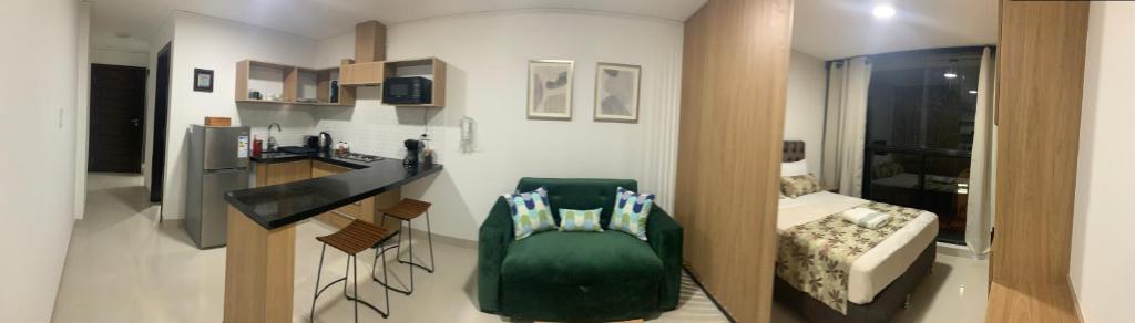 Habitación pequeña con silla verde y dormitorio en “SC Apartments” Equipetrol, en Santa Cruz de la Sierra