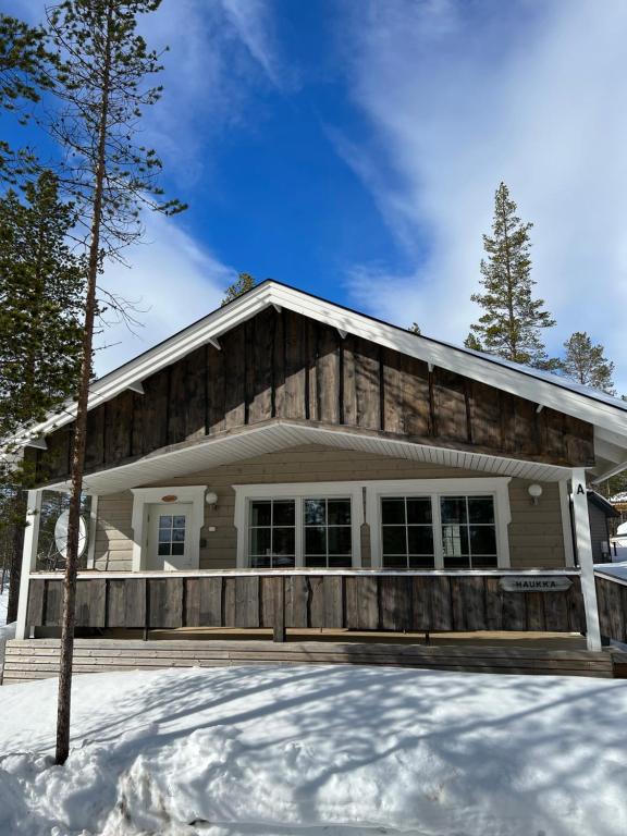 a house with a wooden fence in the snow at Villa Haukka in Saariselka