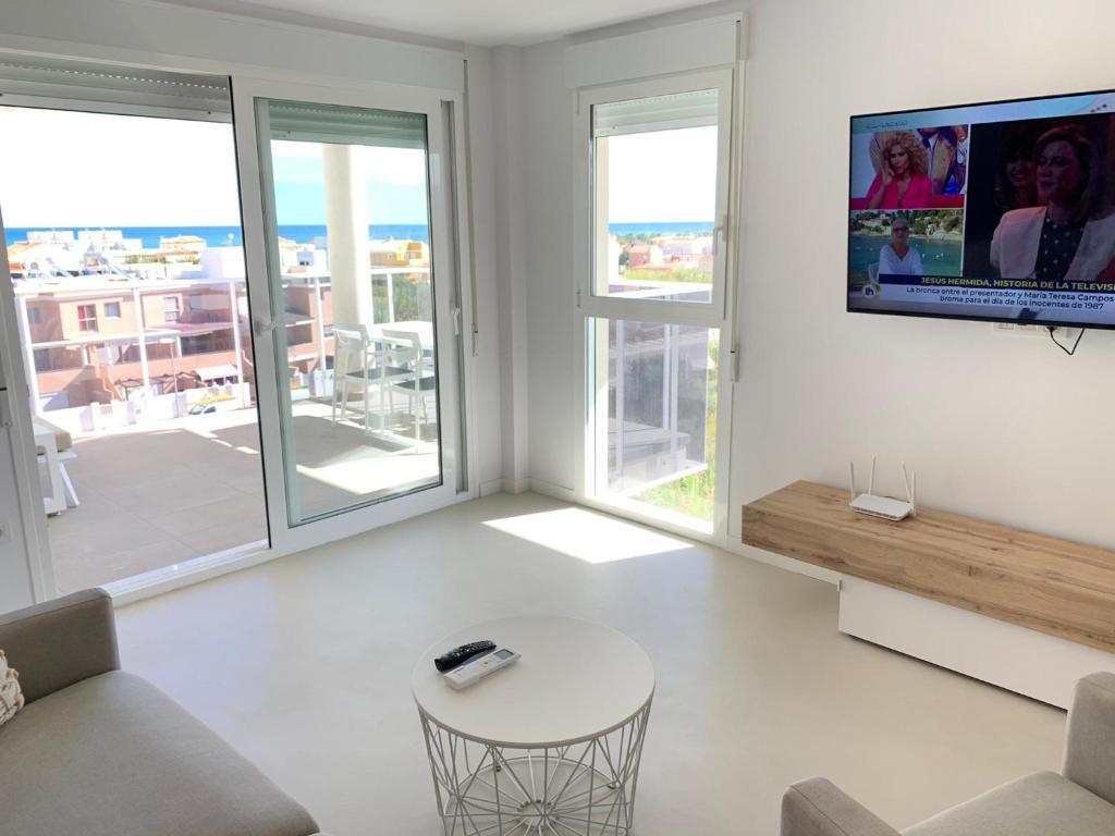 salon z kanapą i telewizorem na ścianie w obiekcie Beautiful apartment with pool near the beach w mieście Oliva