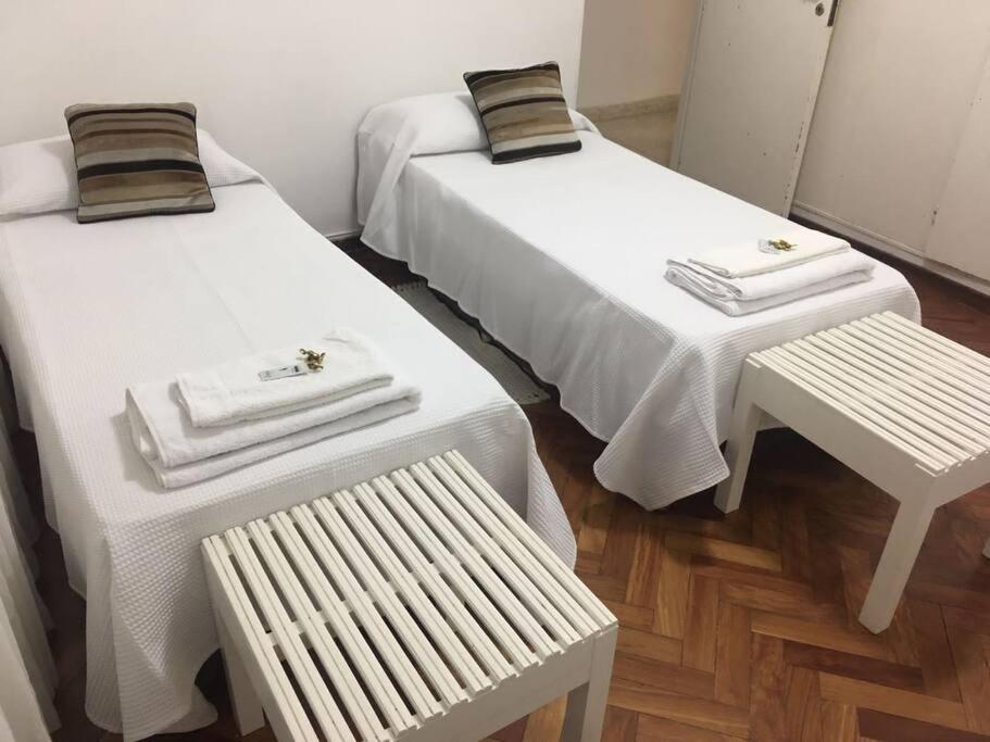 two beds with towels and a bench in a room at Departamento Alvarado in Salta