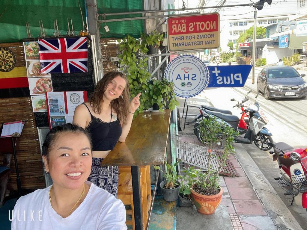 Dwie dziewczyny stoją przed sklepem. w obiekcie Noot's Bar And Guesthouse w mieście Kanchanaburi