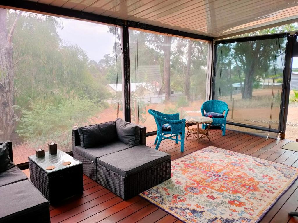 un porche cubierto con sofá y sillas en Warren Retreat - cozy and tranquil 2 brm home, en Nannup
