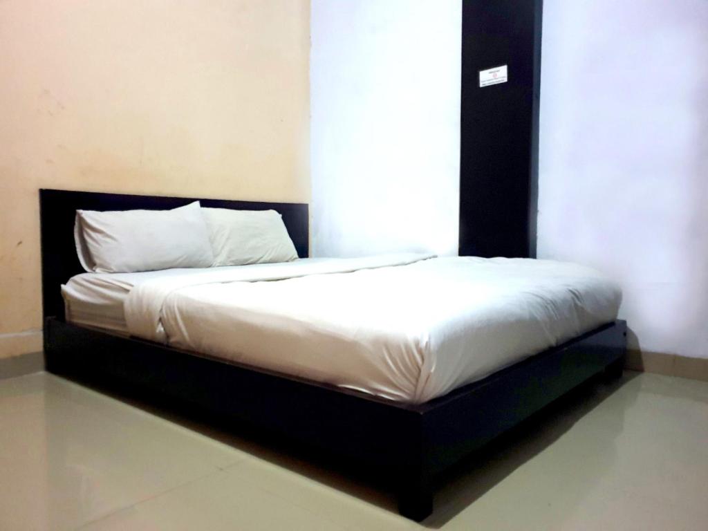 a bed with a black frame and white sheets at Grand Azizah Makassar RedPartner in Makassar