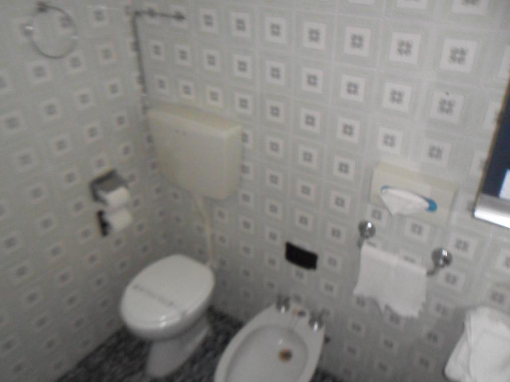 uma casa de banho com um WC branco e um lavatório. em Hotel Giordano Spiaggia em Rimini