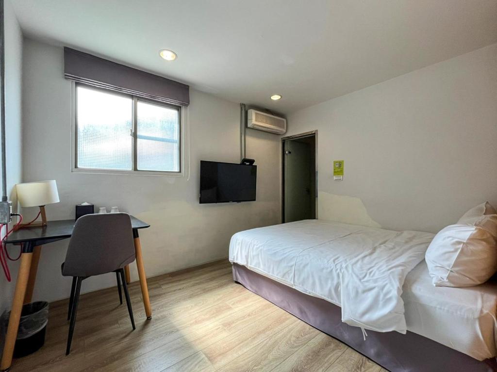 a bedroom with a bed and a desk and a television at Light Hostel in Chiayi City