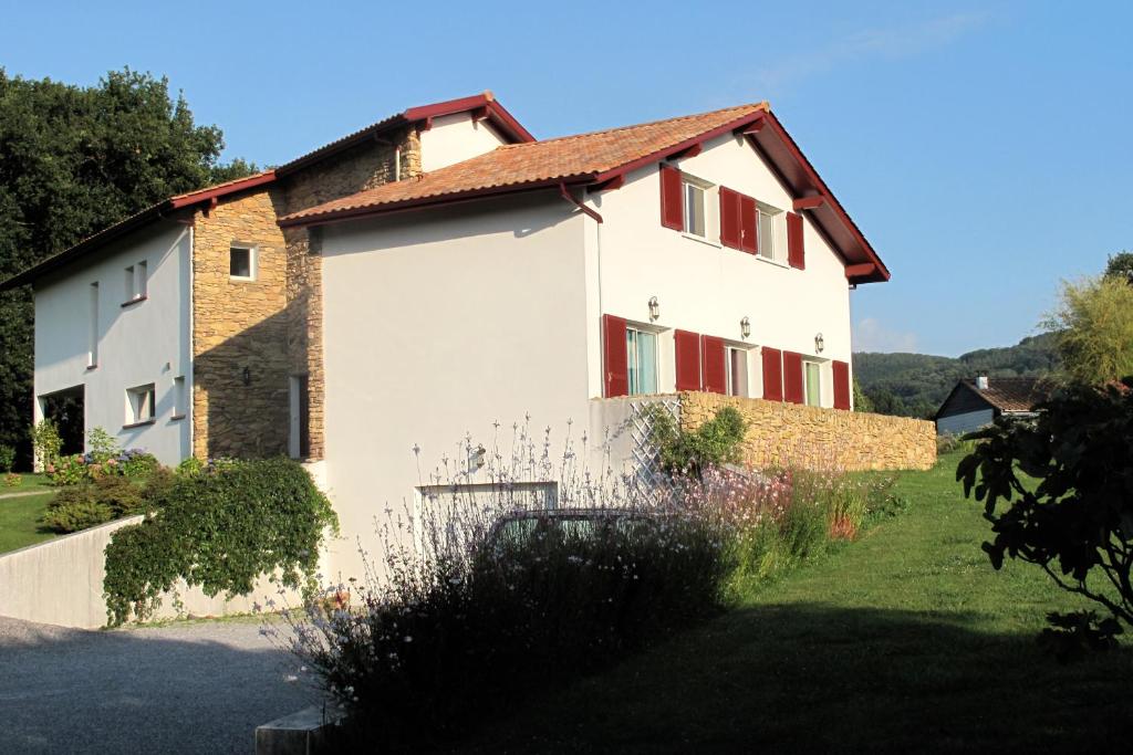 une maison blanche avec des fenêtres rouges et une cour dans l'établissement Apitoki - Chambres d'hôtes au Pays Basque, à Urrugne