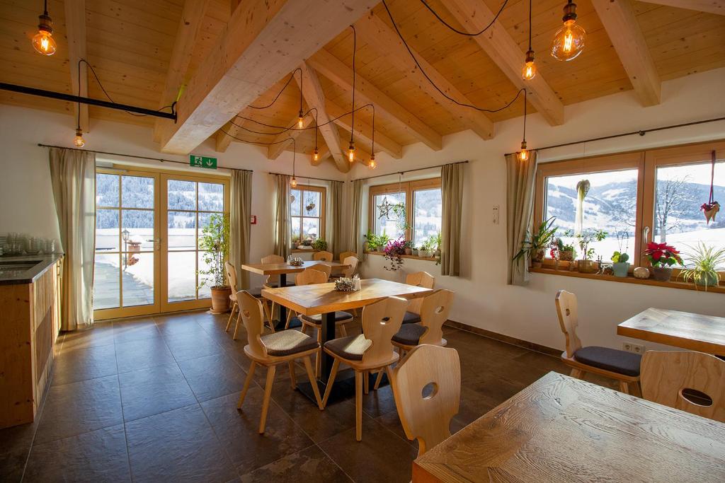 - une salle à manger avec une table, des chaises et des fenêtres dans l'établissement Pension Tannenhof, à Leogang