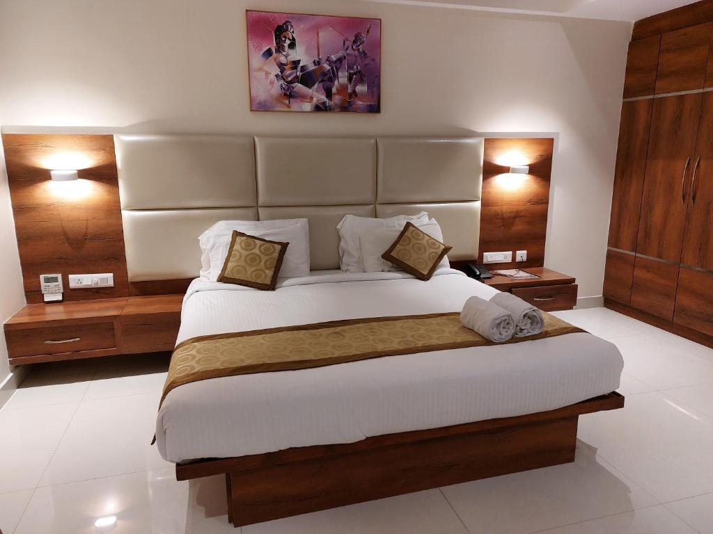 Hotel Tranquil Manipal في مانيبال: غرفة نوم بسرير كبير مع مواقف ليلتين