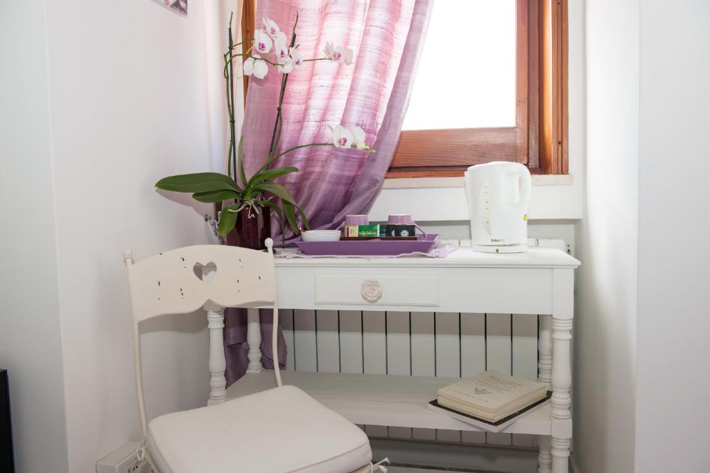 ein weißes Kinderbett mit einem Stuhl und einem Fenster in der Unterkunft I Citri in Taranto