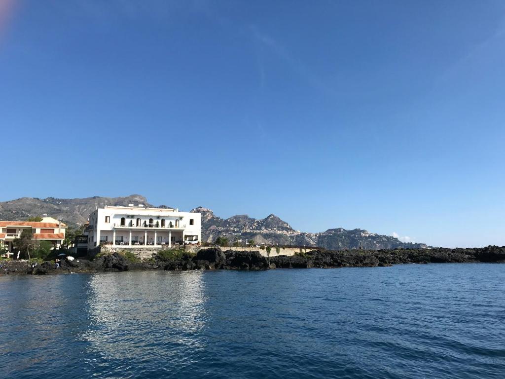 biały budynek na brzegu wody w obiekcie Hotel Orpheus w mieście Giardini Naxos