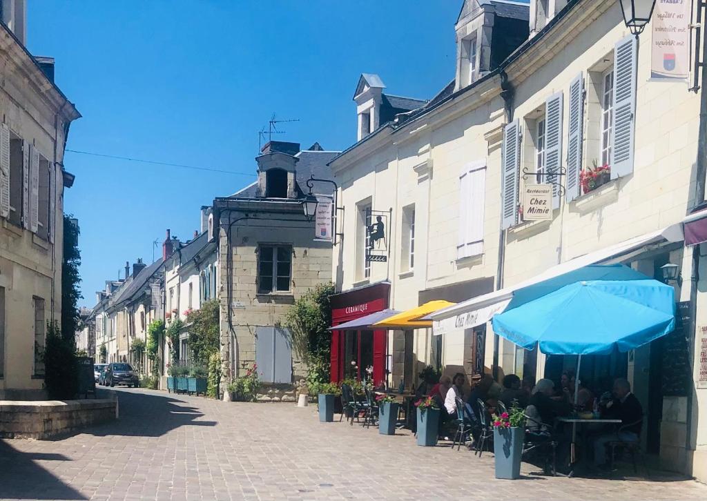 a group of people sitting at tables on a street at Chez mimie les hôtes in Fontevraud-l'Abbaye