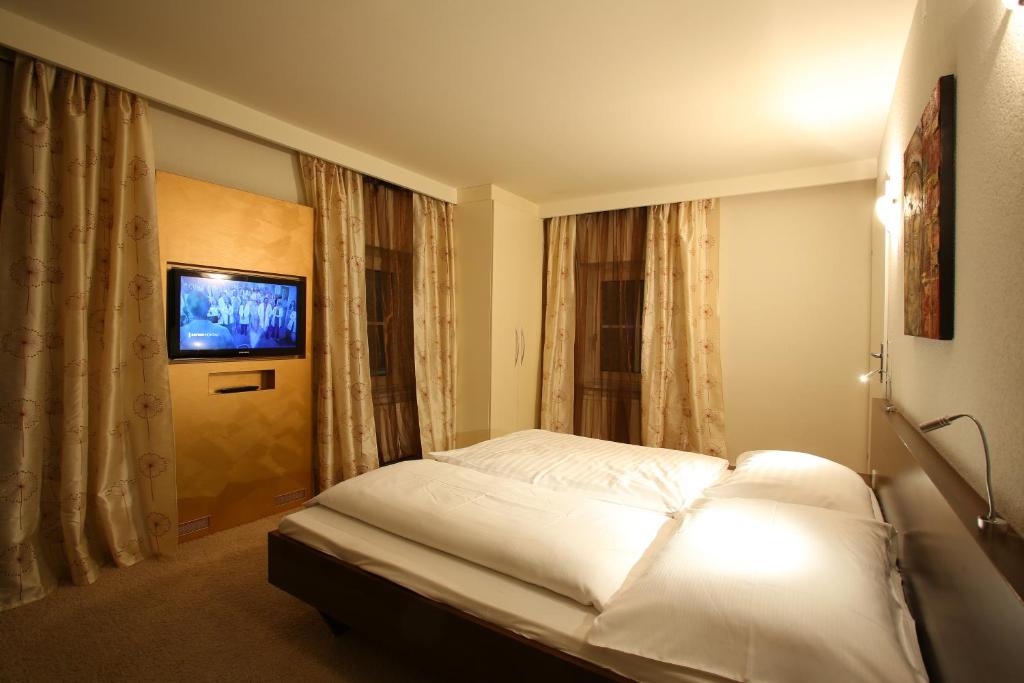 um quarto com uma cama branca e uma televisão em Landgasthof Jagawirt em Kraubath an der Mur