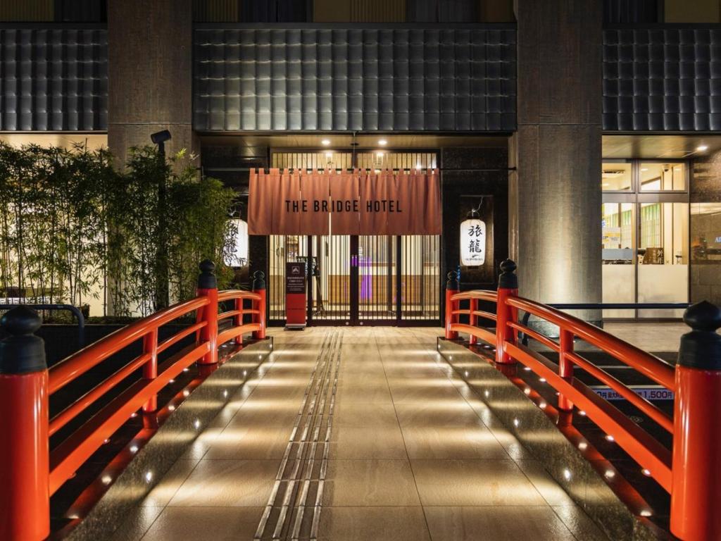 una entrada a un edificio con una puerta roja y una señal en The Bridge Hotel Shinsaibashi en Osaka