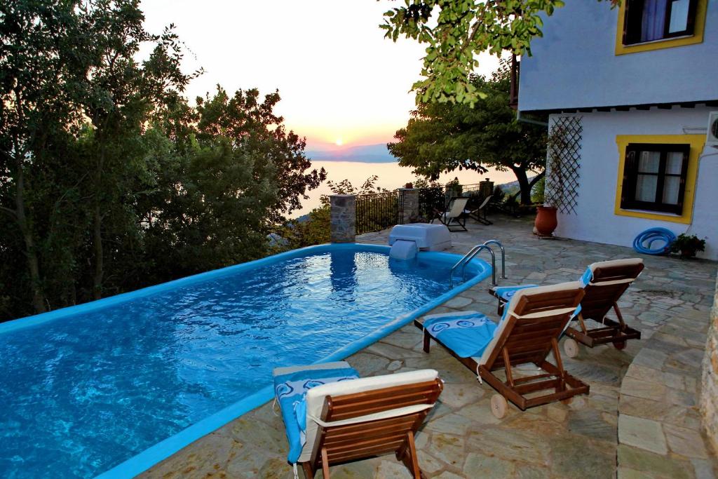 basen z krzesłami i dom w obiekcie Villa Maria O w mieście Skopelos