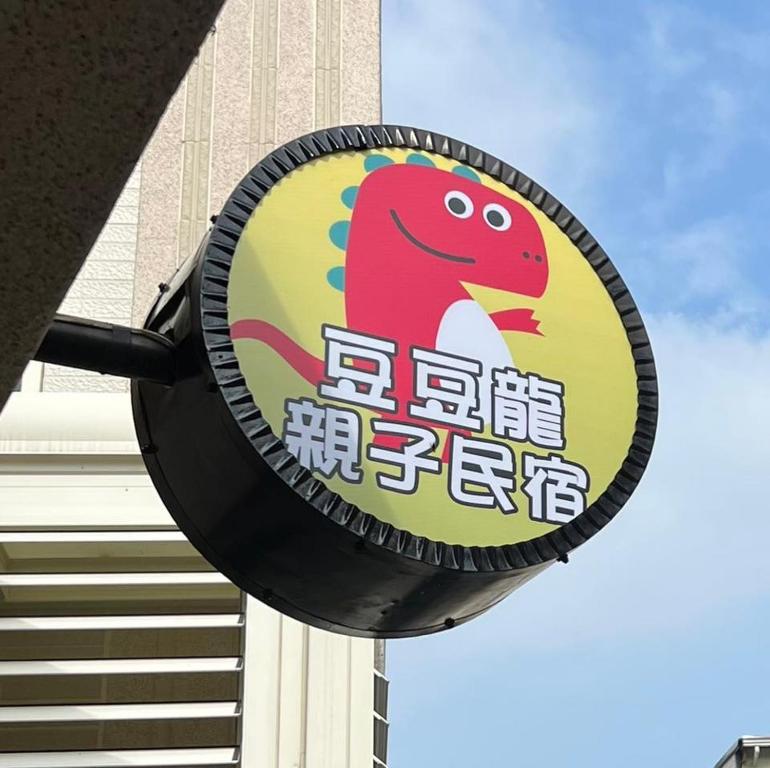 a sign with a dinosaur on it in front of a building at Dou Dou Long Homestay in Donggang