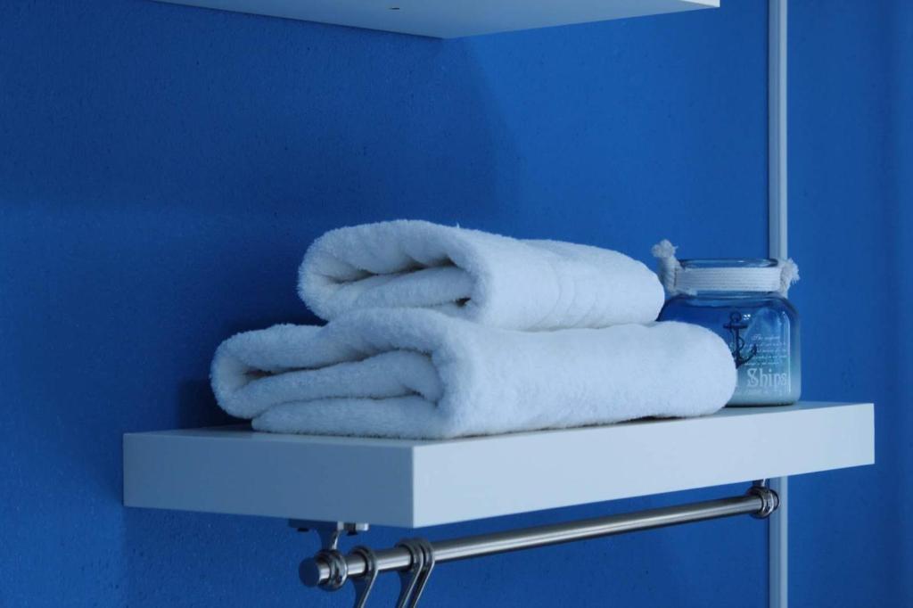 ピルガディキアにあるHotel Elenaのバスルームの棚にタオルを積み重ねる