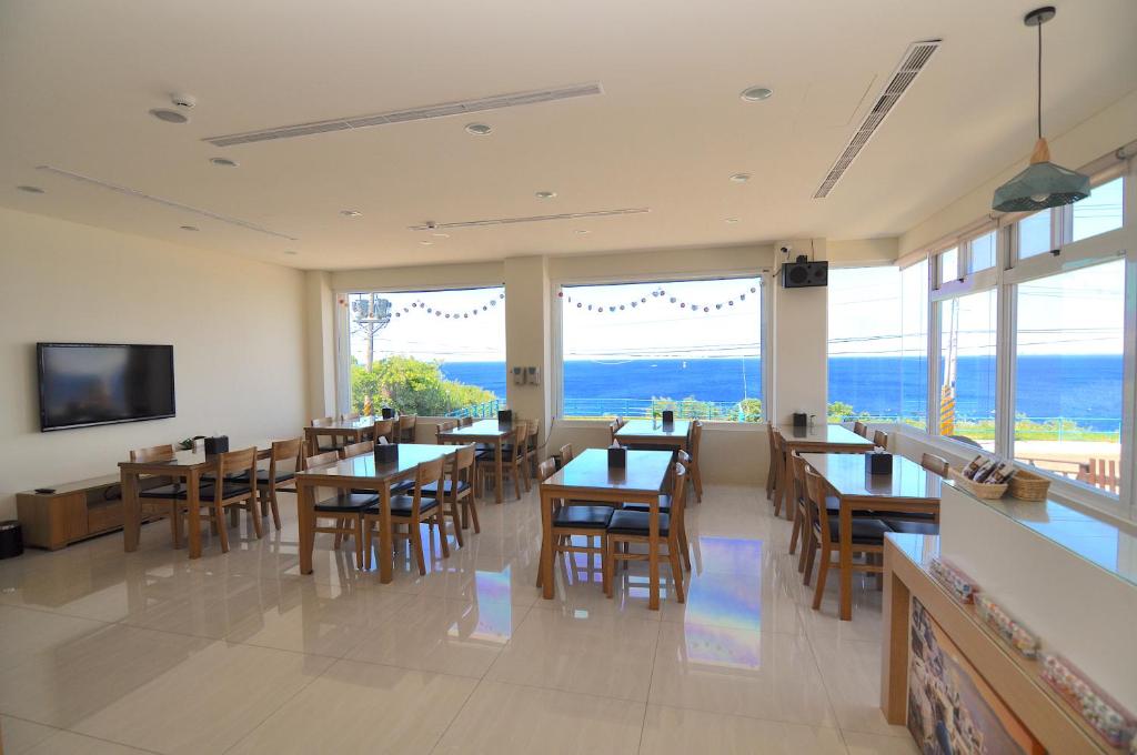 小琉球にあるXinghai Seaview Guesthouseのテーブルと椅子、大きな窓のあるレストラン