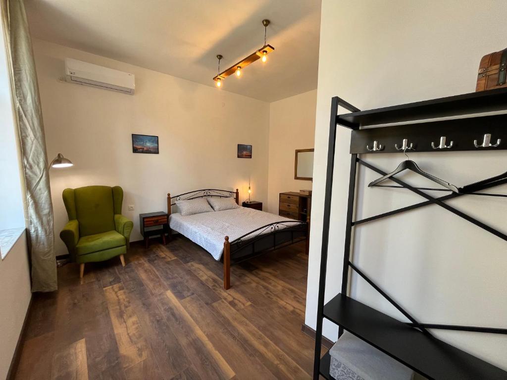 1 dormitorio con 1 cama y 1 silla verde en Prista guest rooms en Ruse