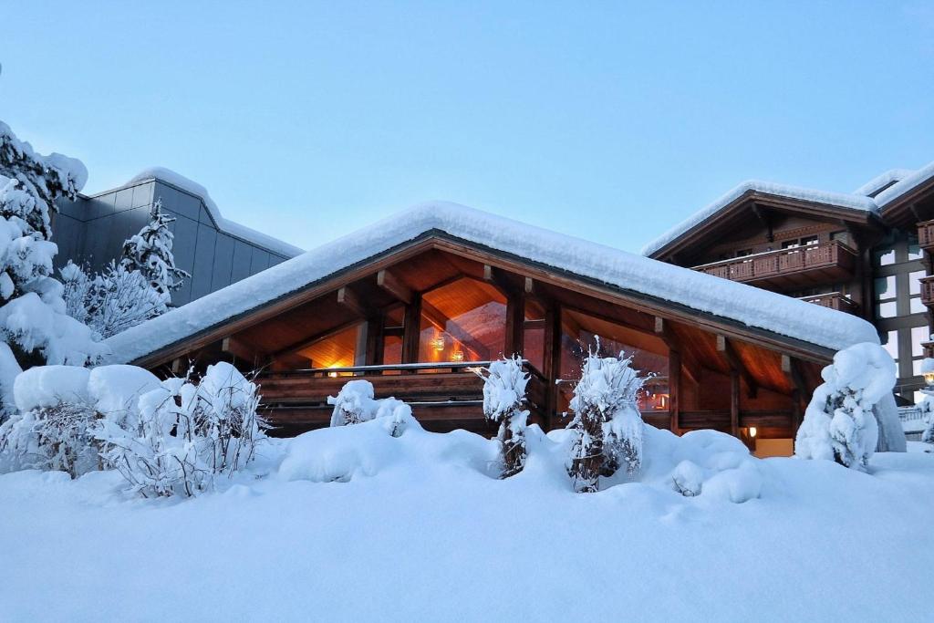 ein mit Schnee bedecktes Blockhaus gedeckte Büsche in der Unterkunft Chalet Morgane in Grindelwald