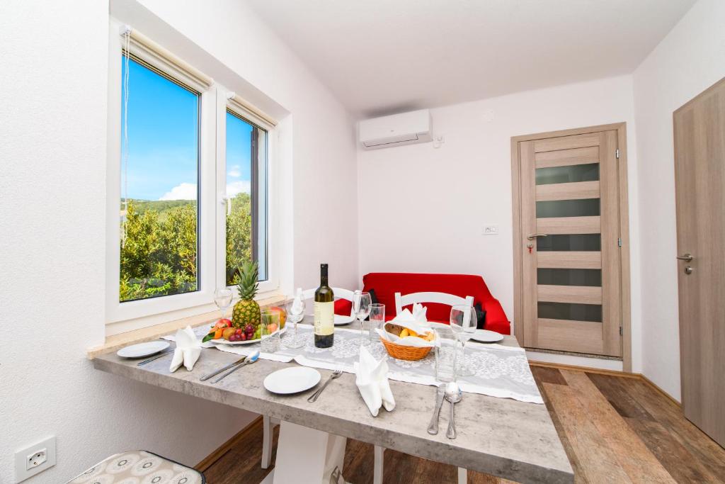 ein Esszimmer mit einem Tisch und einem Fenster in der Unterkunft Apartman Paradiso in Martinšćica