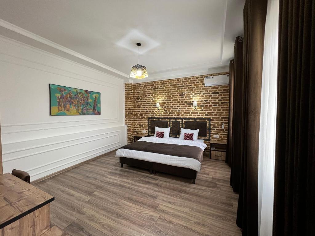 ein Schlafzimmer mit einem Bett und einer Ziegelwand in der Unterkunft The Loft Guest House in Samarkand