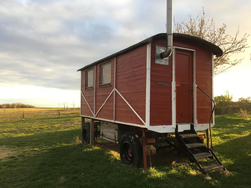 una casa roja en la parte trasera de un camión en un campo en Ferienhof Merbitzer Berg, en Löbejün