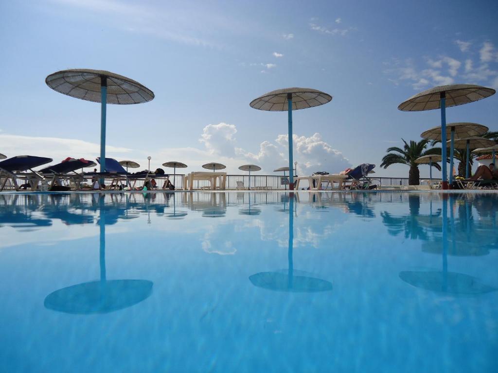 een zwembad met parasols, tafels en stoelen bij Corfu Sea Gardens Hotel in Kavos