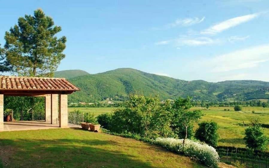 un edificio en un campo con montañas en el fondo en Villa Bagnaie, en Lisciano Niccone