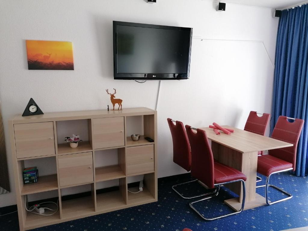 Habitación con mesa y TV en la pared. en Kranichsee-Apartment en Goslar