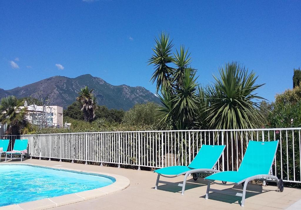 2 chaises et une piscine avec des montagnes en arrière-plan dans l'établissement Kazamasavani - Belle maison proche mer, à Cervione