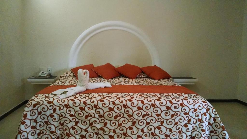 a bed with a doll laying on top of it at Hotel Plaza Hidalgo in Ixtlán del Río