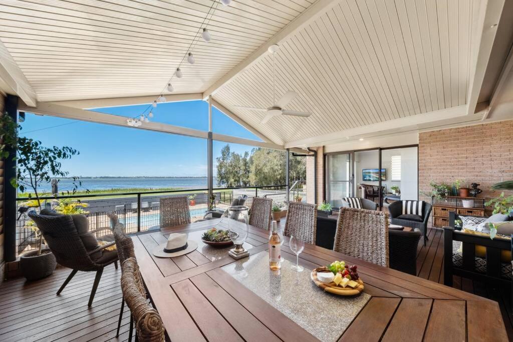 una sala da pranzo con tavolo e vista sull'oceano di The Lake House - Luxury home with Pool a Berkeley Vale