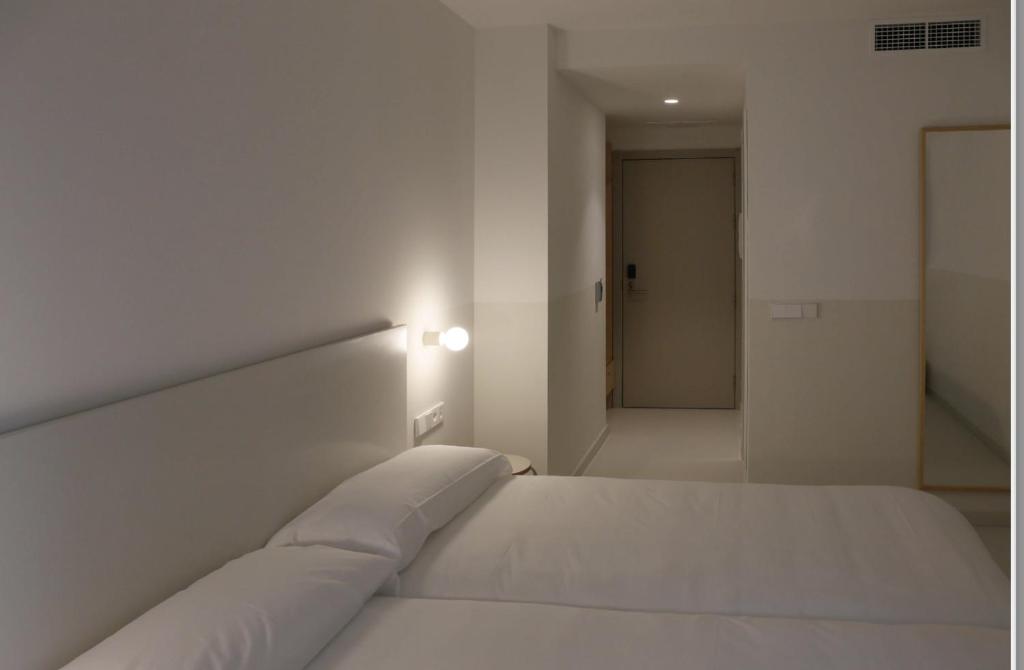 a white bed in a white bedroom with a hallway at HOTEL LA FONDA B&B in Tarazona de Aragón