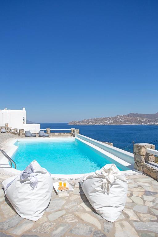 a swimming pool with chairs next to the water at Villa BiancaRosa with amazing views! in Mikonos
