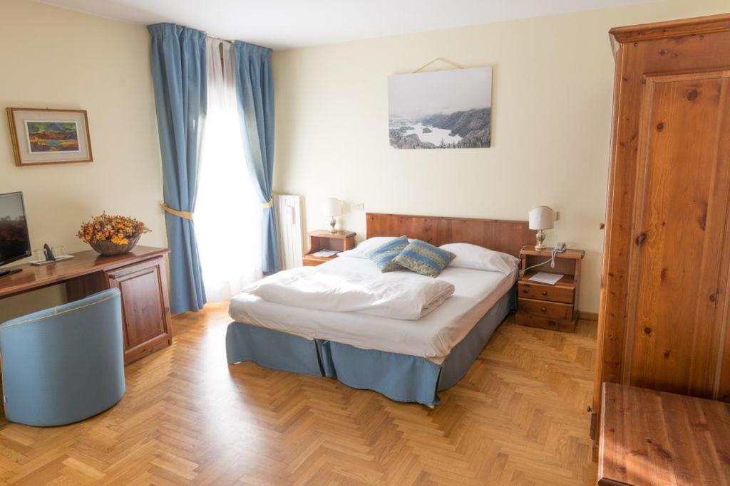 um quarto com uma cama e uma televisão num quarto em Hotel Belvedere Dolomiti em Pieve di Cadore