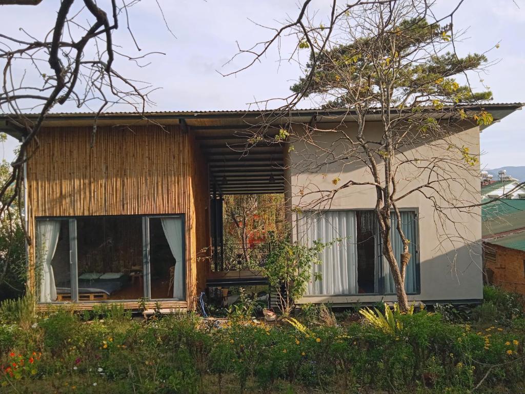 uma pequena casa com uma grande janela e uma árvore em Komori House em Da Lat