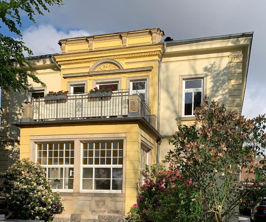 Una casa amarilla con balcón en la parte superior. en Helle Terrassenwohnung in Traumlage von Dresden, en Dresden