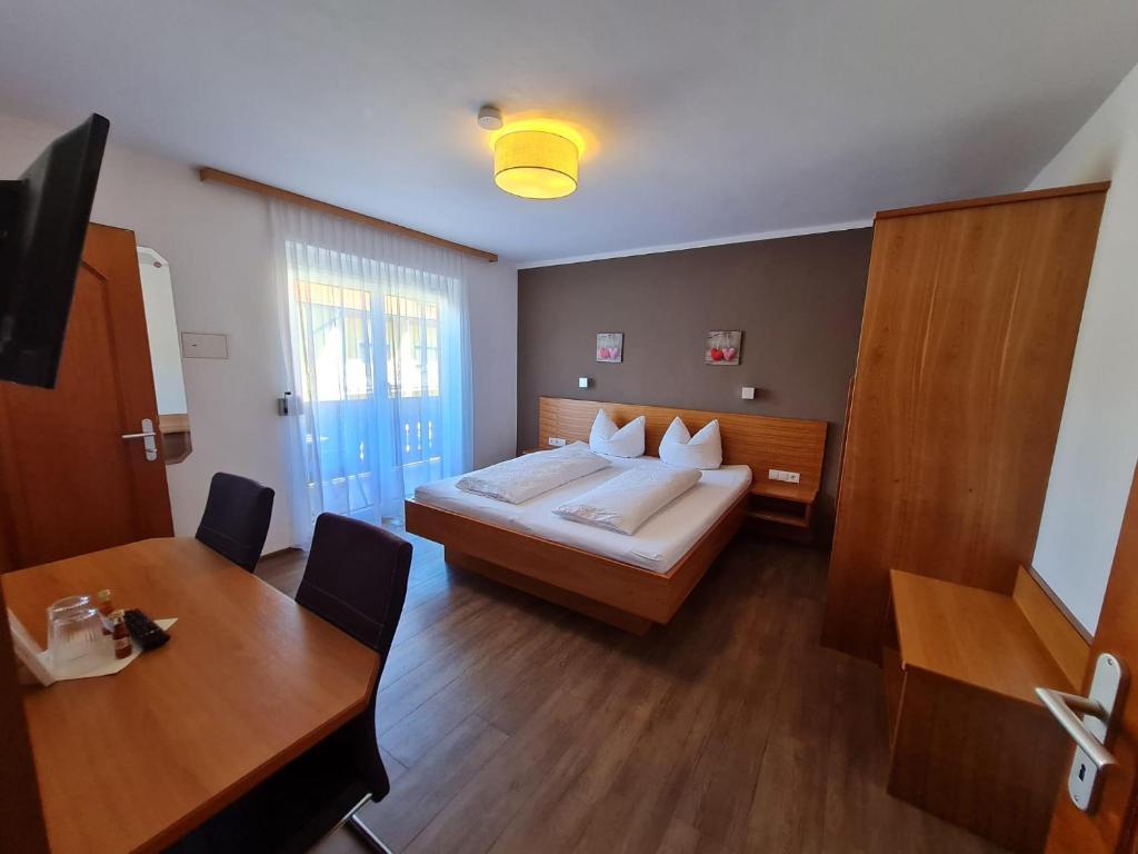 a bedroom with a bed and a table and a desk at Pension Tulpe in Sankt Kanzian