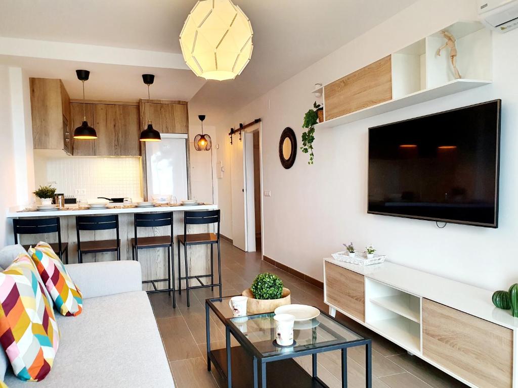 een woonkamer met een bank en een tv aan de muur bij Mallorca Seaviews Apt in Torremolinos
