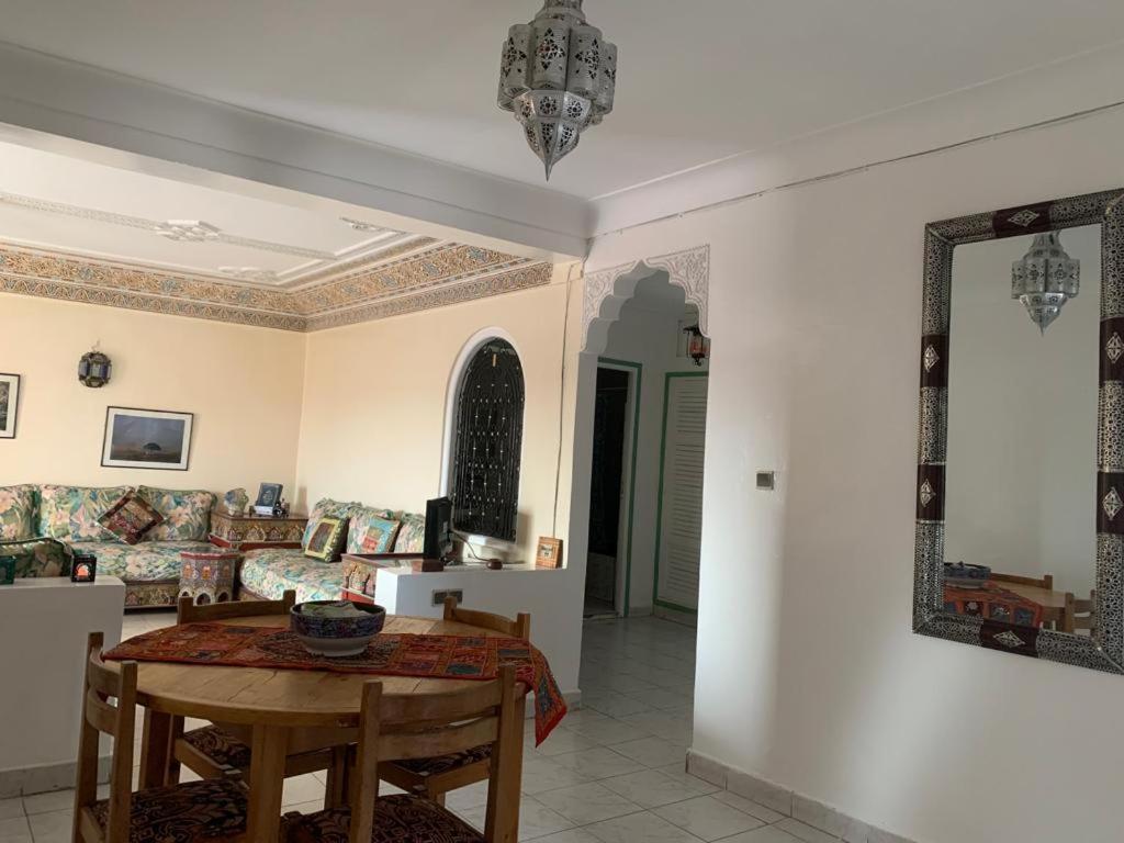 ein Wohnzimmer mit einem Tisch und einem Sofa in der Unterkunft APPARTEMENT PERLE RARE AU CENTRE DE MARRAKECH in Marrakesch