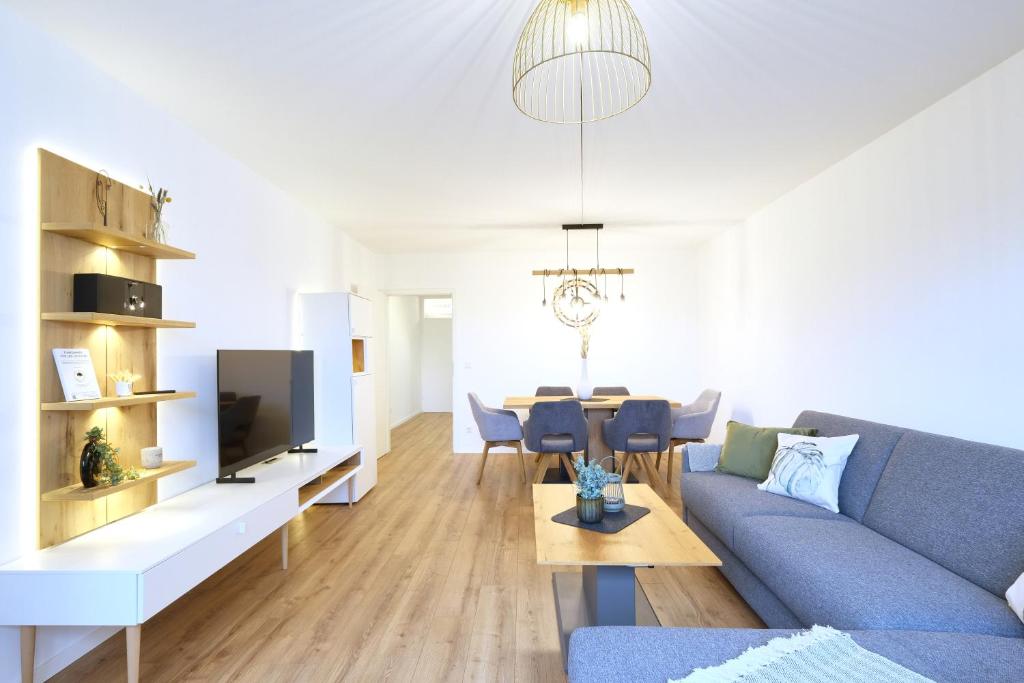 a living room with a blue couch and a table at Topeingerichtete große 2-Zimmer Wohnung in Immenstaad am Bodensee