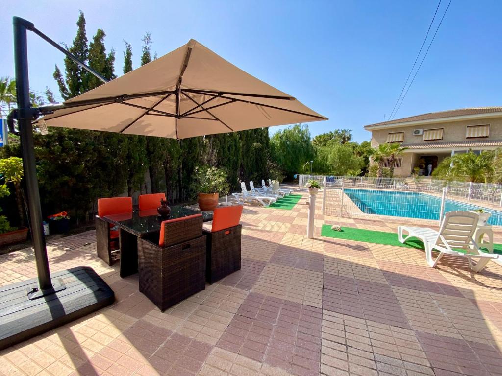 patio z parasolem i krzesłami oraz basenem w obiekcie Stunning 5 bed Villa La Font, private pool w mieście El Campello