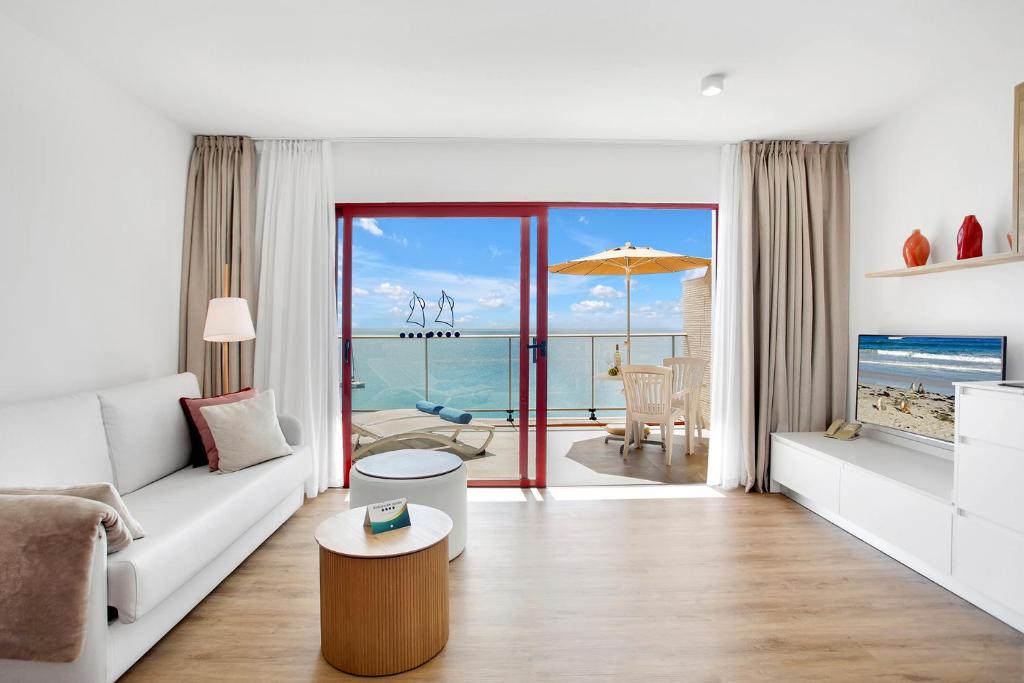 a white living room with a view of the ocean at Apartamentos Atalaya de Jandía by LIVVO in Morro del Jable