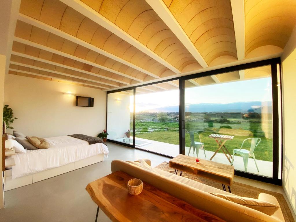 uma sala de estar com uma cama e uma grande janela em Estrellas de Gredos em Arenas de San Pedro
