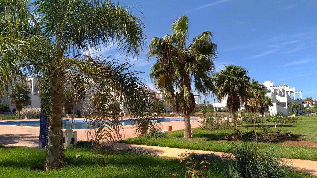 een resort met een zwembad en palmbomen bij Chez Younès Appartement Marina Saidia Ap8 in Saidia 